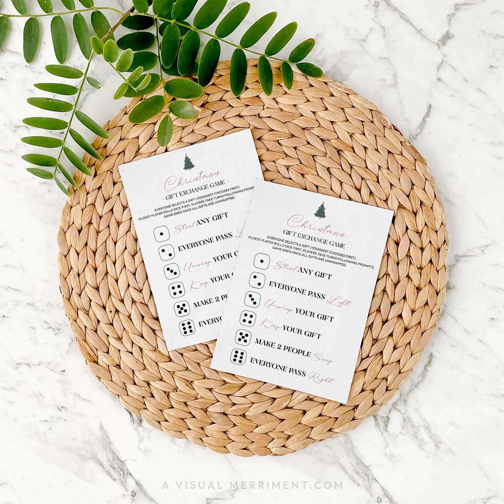 2 modern christmas roll the dice gift exchange game cards on a woven placemat with green leaves