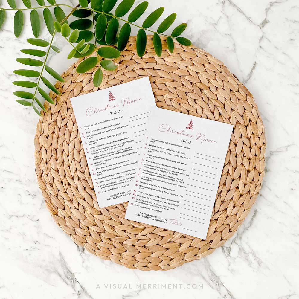 2 modern christmas movie trivia cards on a woven placemat with green leaves