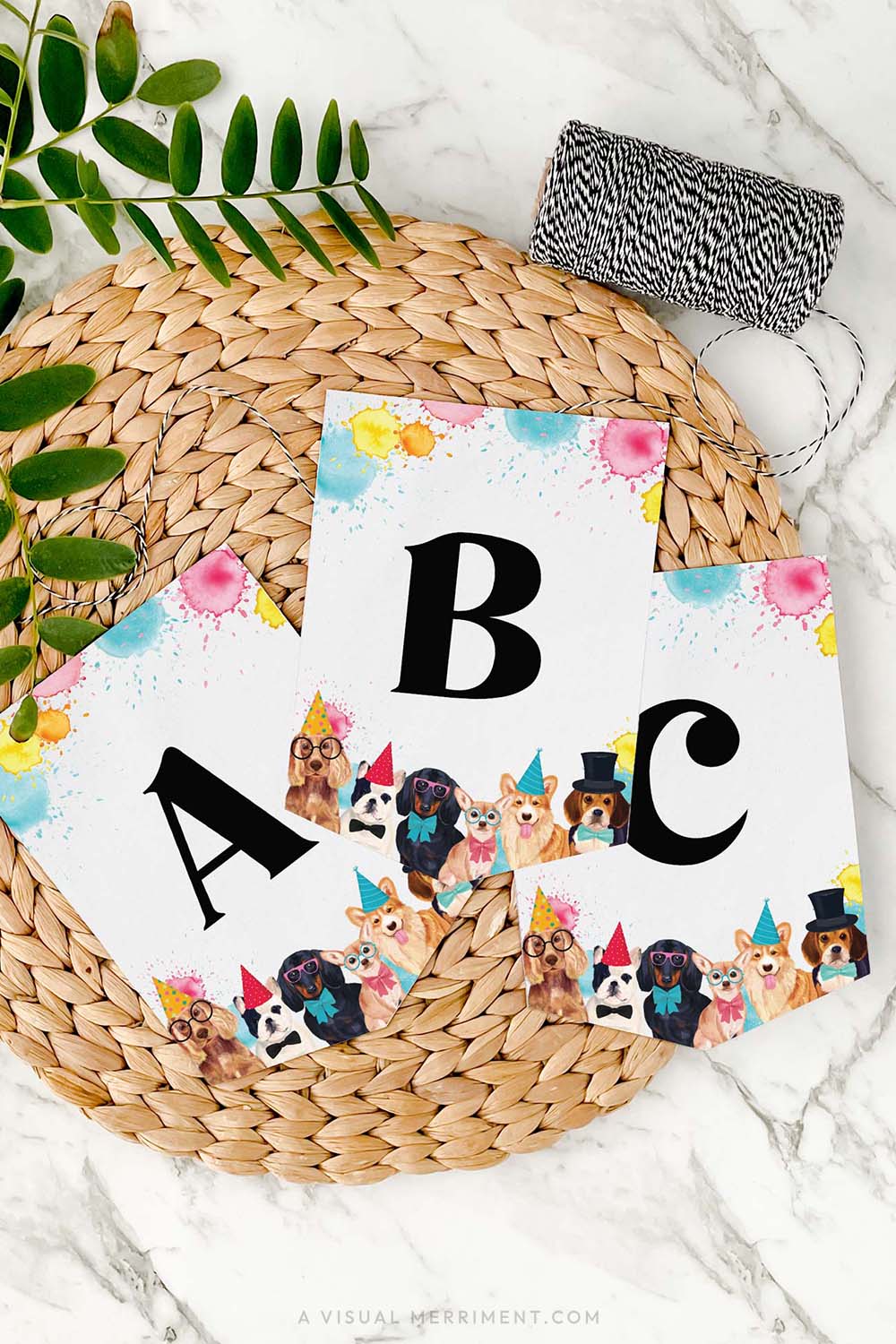 set of 3 letter banner flags with paint splatter dogs in party hats design on mat with twine and leaves