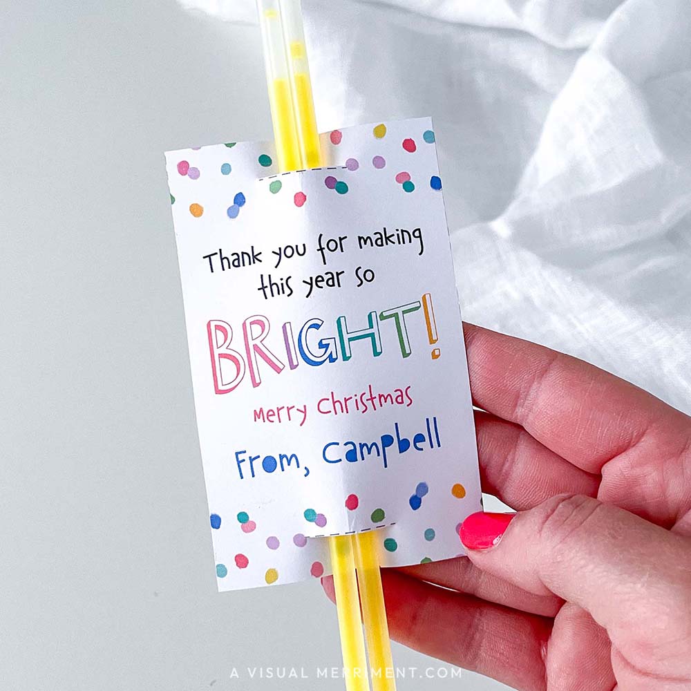 Hand holding 'thank you for making this year bright' merry christmas glow stick holder with sticks in polka dot design