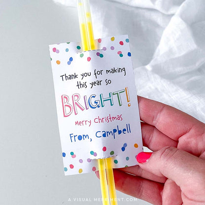 Hand holding 'thank you for making this year bright' merry christmas glow stick holder with sticks in polka dot design