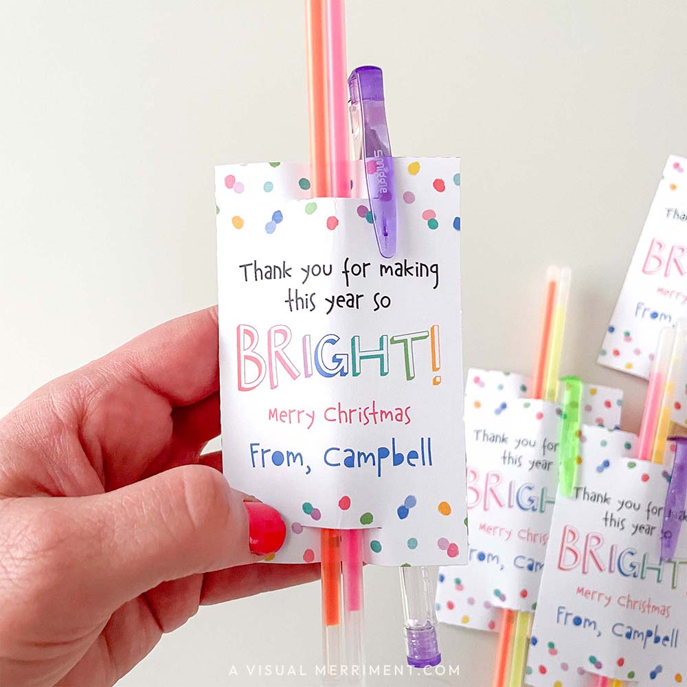 hand holding christmas appreciation gift tag with glow sticks and pen inserted.