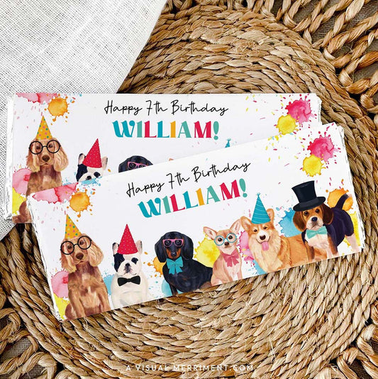 2 custom chocolate wrappers on candy bars with colorful party dogs and paint splatters laid on a woven mat