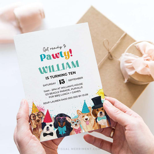 hands holding invitation with dogs wearing party hats and gifts in background