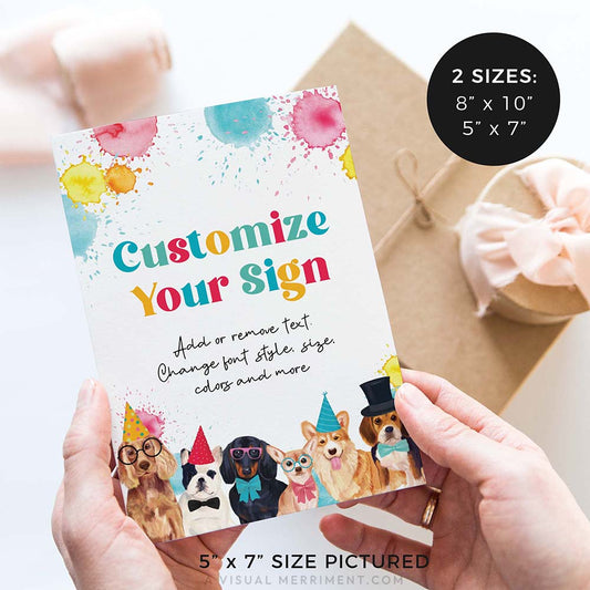 hands holding birthday party sign with dogs wearing party hats and gifts in background
