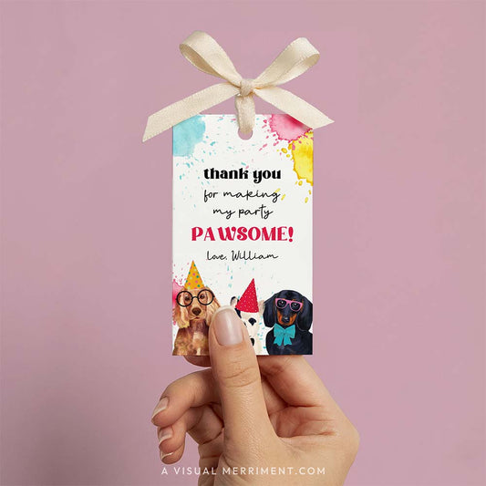 Hand holding party favor gift tag with party dogs and paint splatters