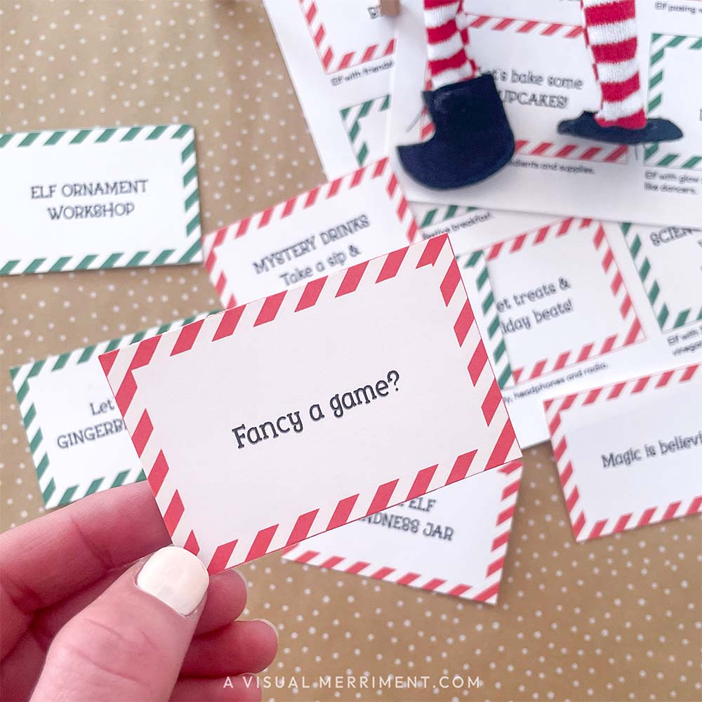 hand holding printed elf on the shelf note "fancy a game" with other notes and elf legs in background