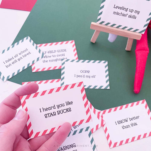 hand holding red funny elf on the shelf idea sign with other signs scattered