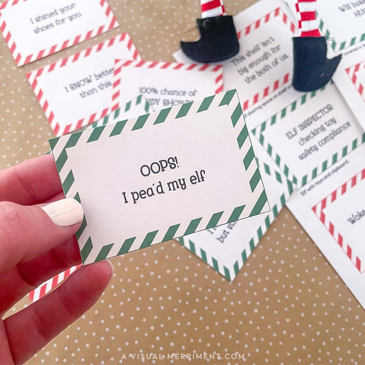 hand holding red funny elf on the shelf idea sign with other signs scattered