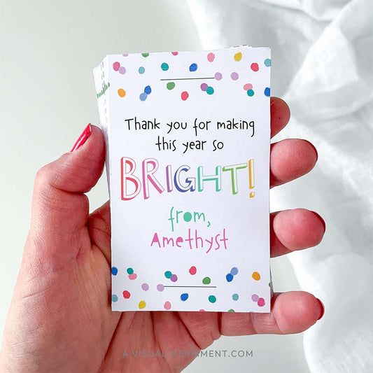 Hand holding pack of cards that say 'thank you for making this year bright' in colorful rainbow confetti polka dot design