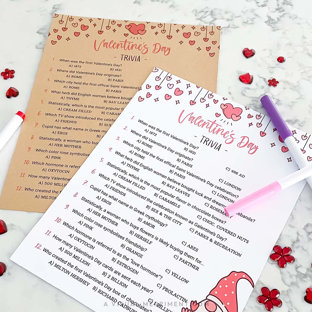 Two Valentine's Day trivia sheets with a pen on a marble surface.