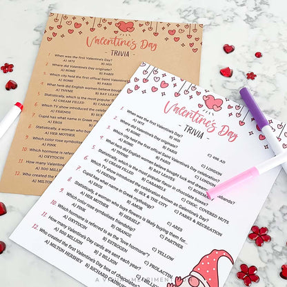 Two Valentine's Day trivia sheets with a pen on a marble surface.