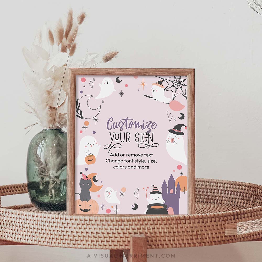 printable pink ghost halloween sign sits in frame on rattan table with vase of reeds