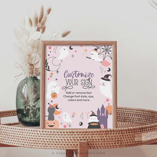 printable pink ghost halloween sign sits in frame on rattan table with vase of reeds