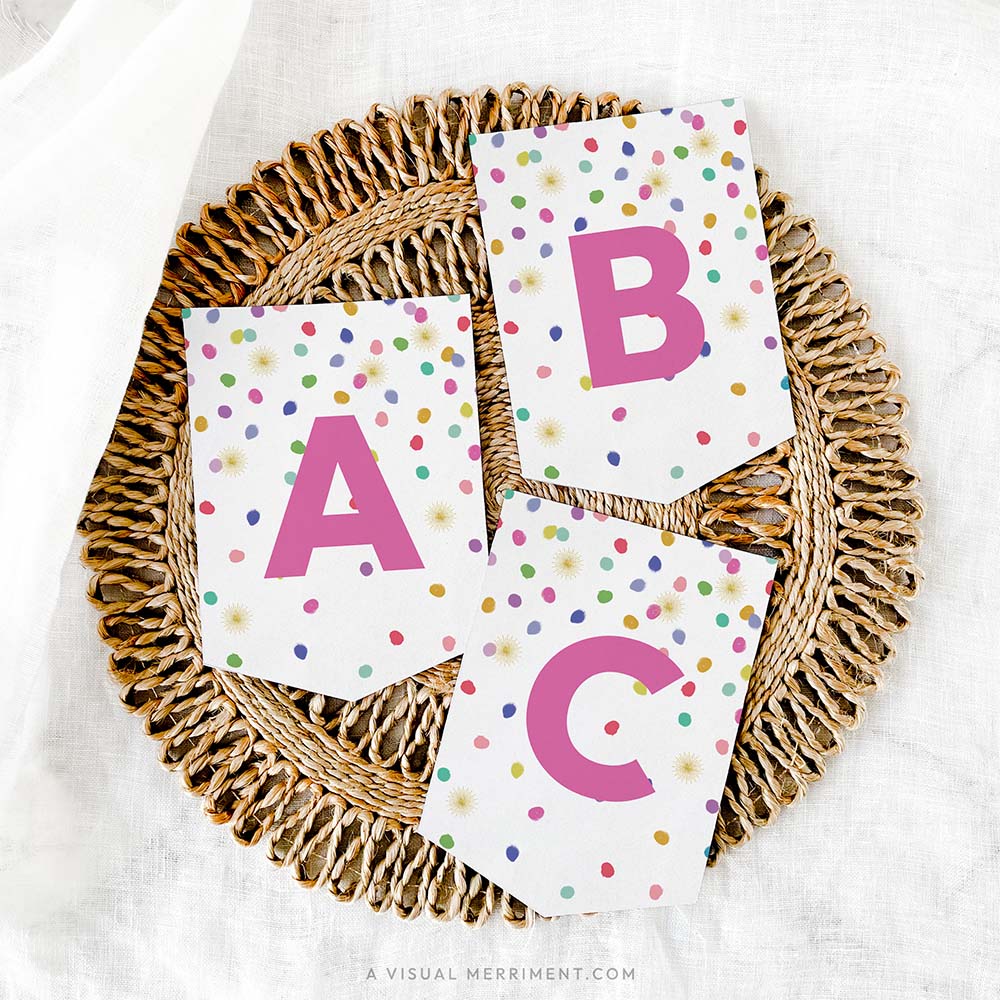 set of 3 letter banner flags with colorful polka dot rainbow confetti design on grass mat