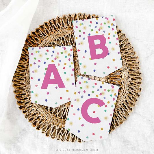 set of 3 letter banner flags with colorful polka dot rainbow confetti design on grass mat