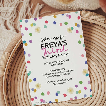 colorful rainbow confetti printed invitation template sitting on a boho style table