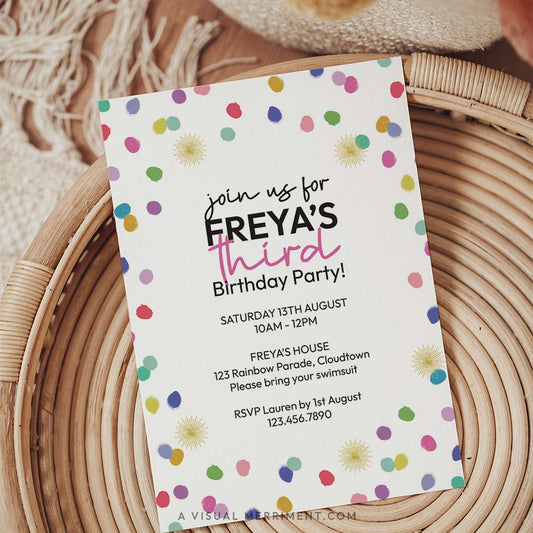 colorful rainbow confetti printed invitation template sitting on a boho style table