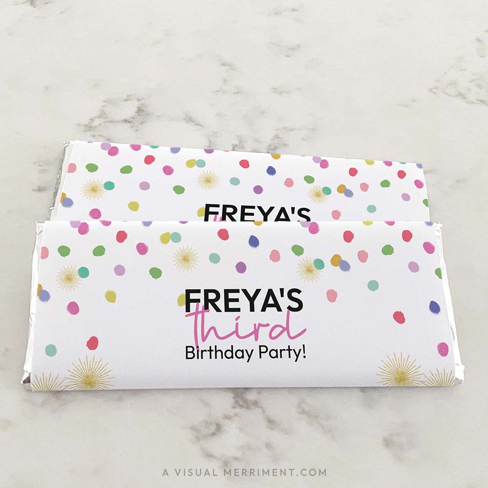 2 stacked candy bars on marble surface wrapped with colorful rainbow confetti custom chocolate wrappers