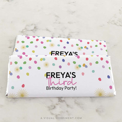 2 stacked candy bars on marble surface wrapped with colorful rainbow confetti custom chocolate wrappers