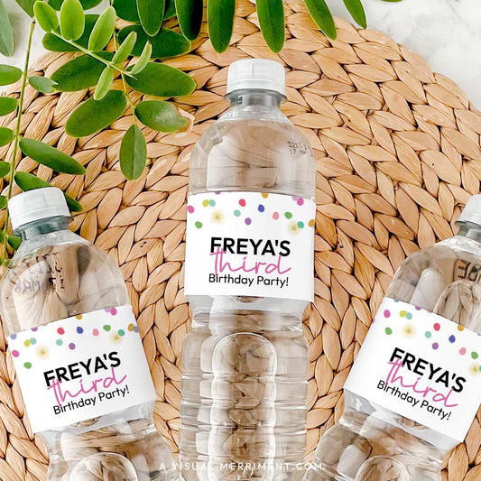 3 bottles with rainbow confetti custom water bottle labels in polka dot design on grass mat with leaves