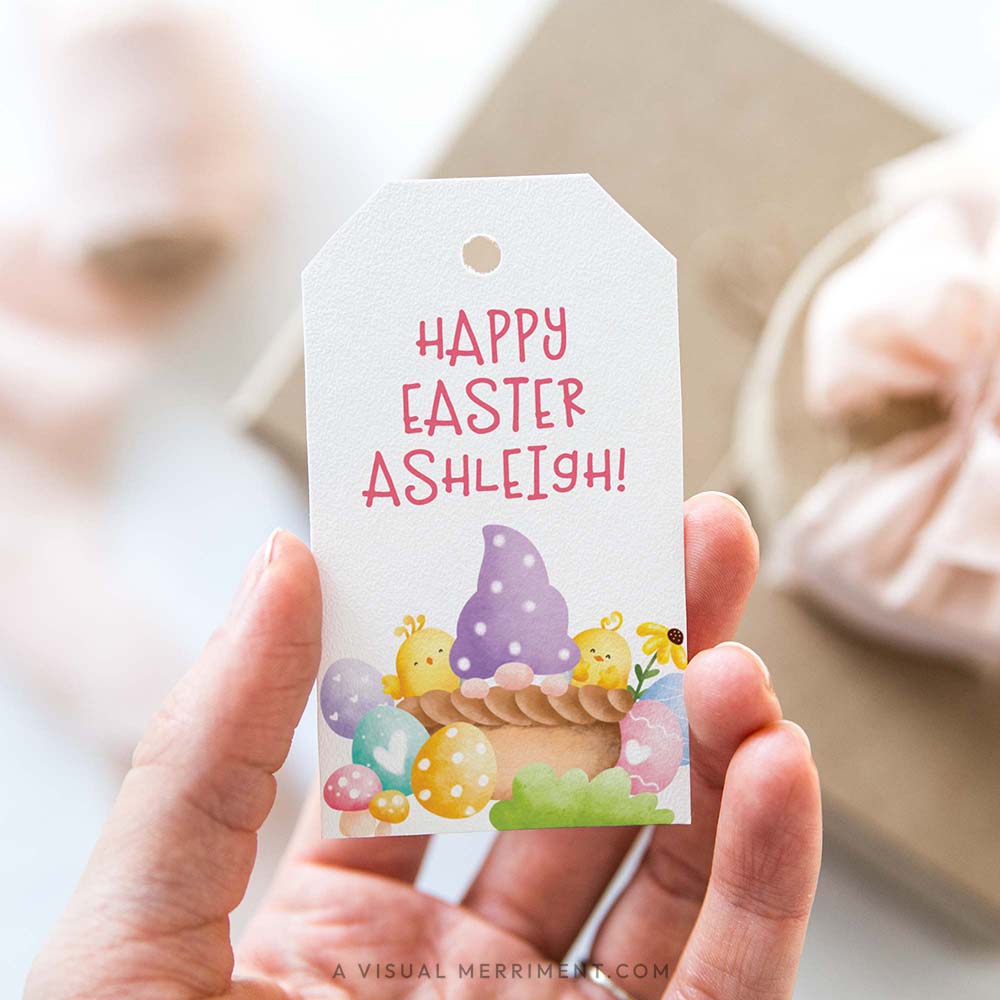 Hand holding a personalized Easter gift tag with a colorful purple basket gnome design