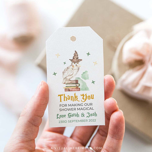 Hand holding baby shower printable gift tag with owl and books design in a harry potter style theme