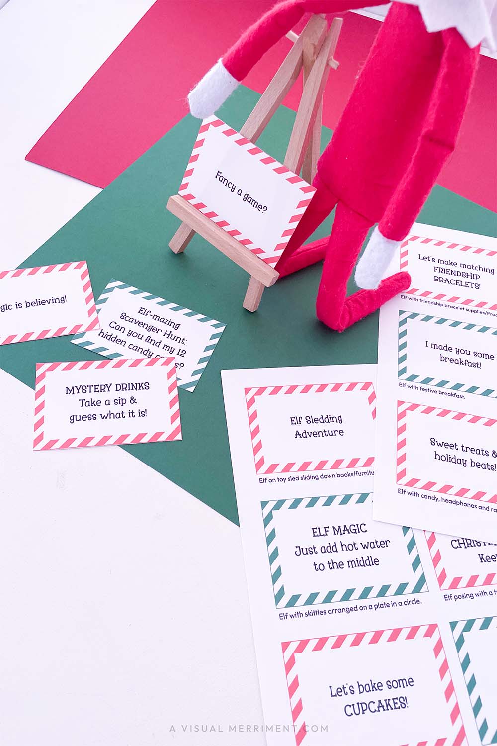 Vertical of red and green activity & kindness elf on the shelf ideas signs on easel next to elf doll