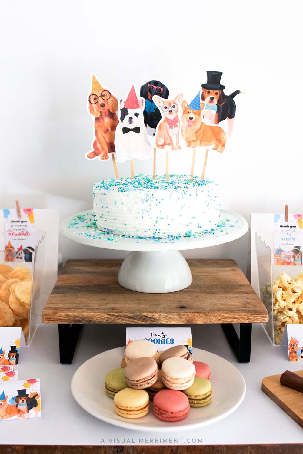 party dog cake toppers on cake on party table with signs and party treats