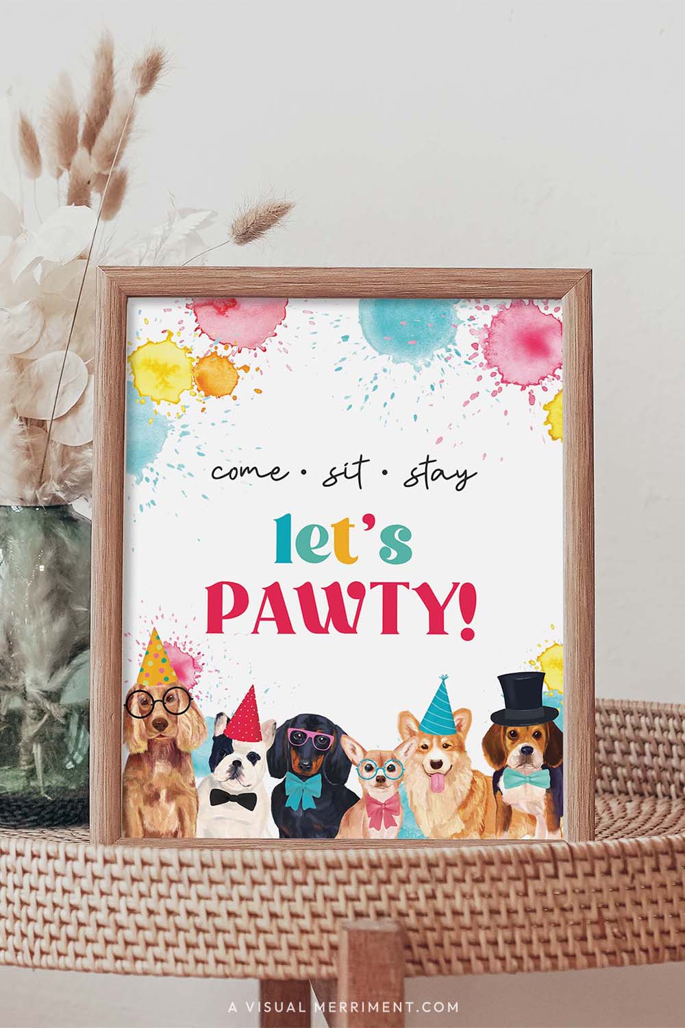 let’s pawty party dog printable party sign in a frame sitting on a grass table with a vase of boho stems