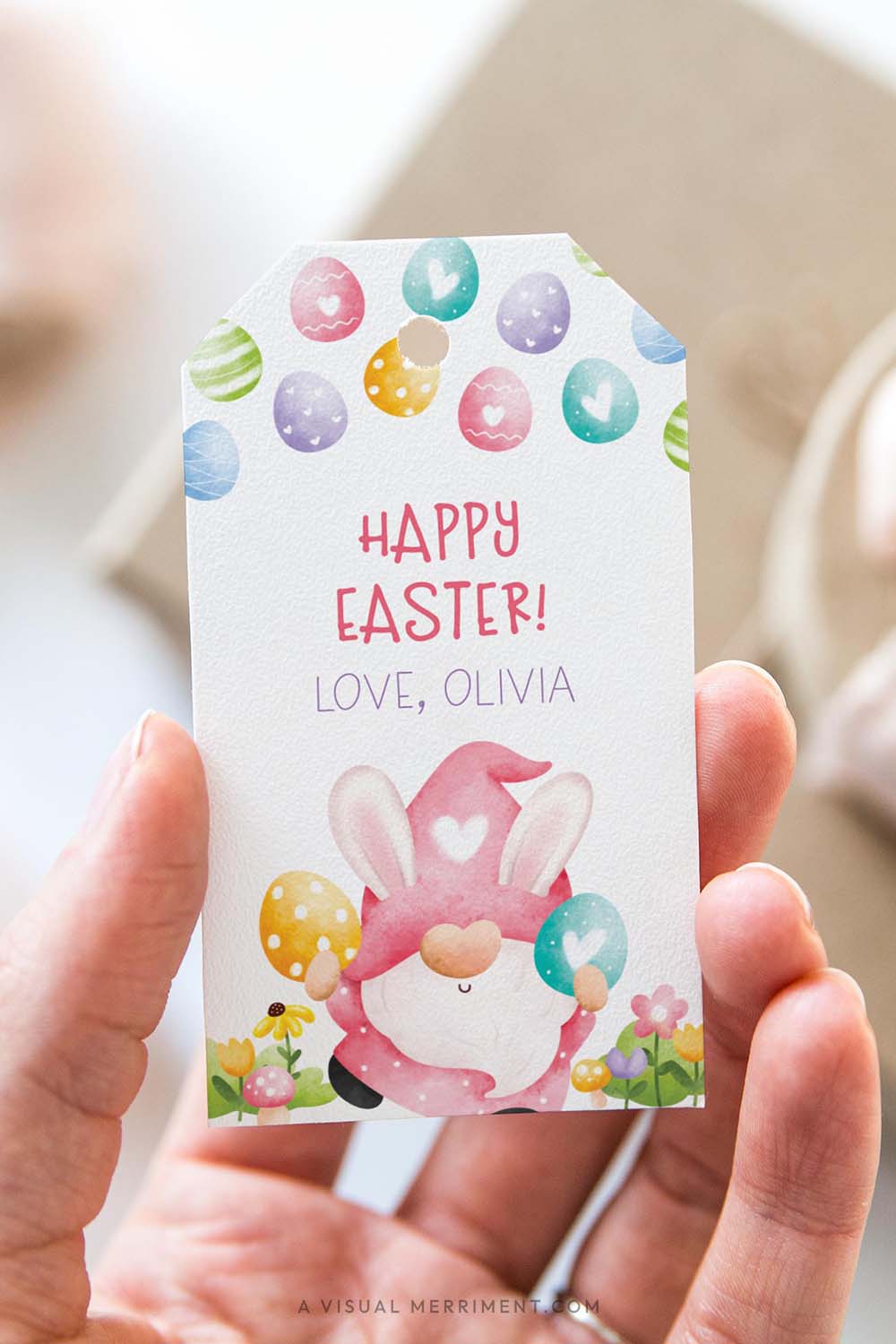 vertical of Hand holding a personalized Easter gift tag with a colorful pink gnome design