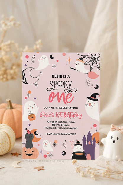 vertical of pink spooky one birthday invitation with ghosts, pumpkins, stars in a celestial design against neutral fall setting