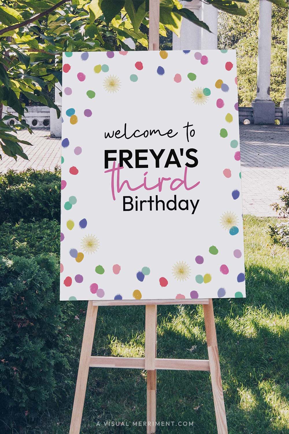 Vertical Large custom welcome sign with colorful rainbow confetti polka dots on an easel outdoors.