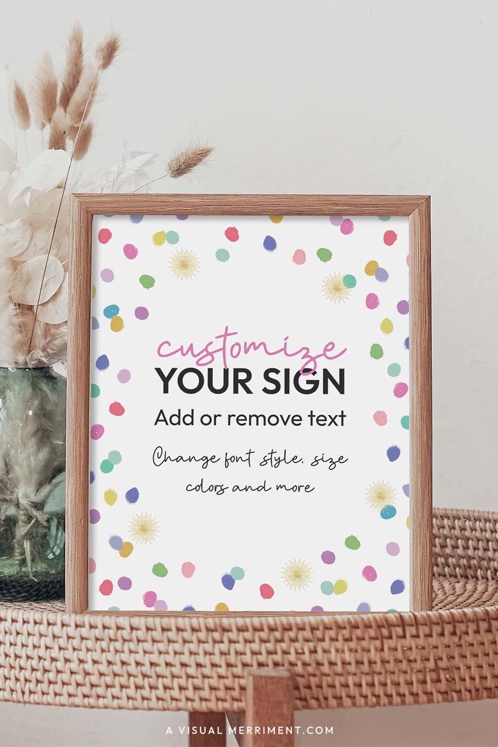 colorful rainbow confetti polka dots party sign in a frame sitting on a grass table with a vase of boho stems