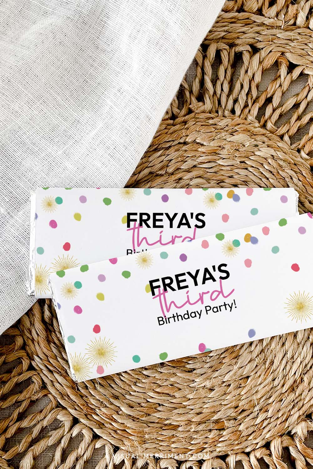 Vertical of custom chocolate wrappers on candy bars with colorful rainbow confetti laid on a woven mat